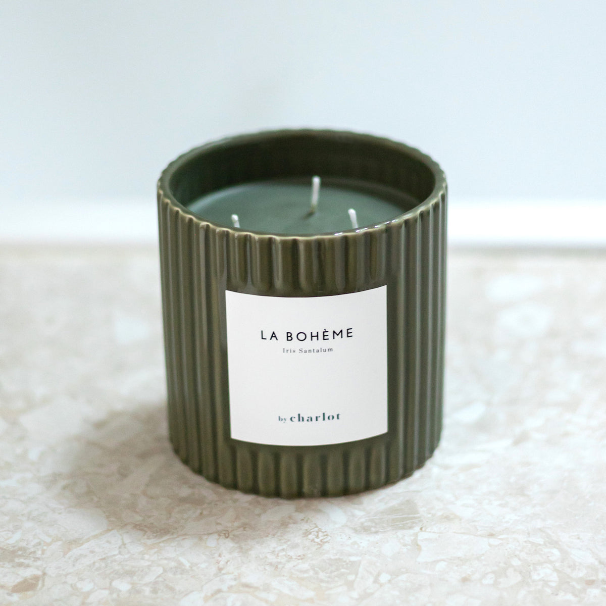 Bougie La Bohème grand format, pot cannelé vert olive posé sur un marbre